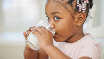 Petite fille qui boit un verre de lait de profil
